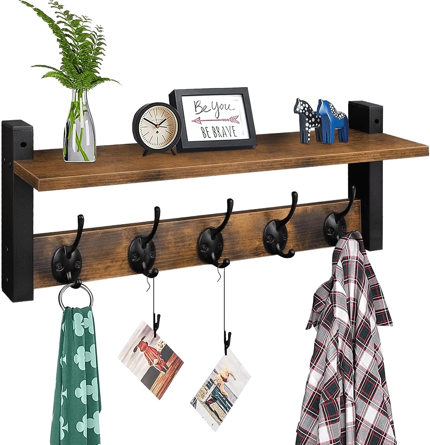 Wood coat rack with a top shelf and five black hooks mounted in an entryway holding jackets and a bag